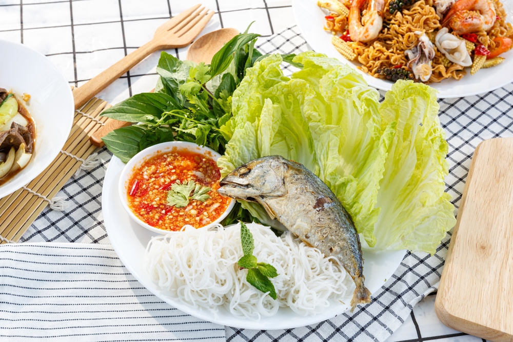 Fried mackerel served with fresh vegetables, rice vermicelli, spicy sauce, and rice noodles.