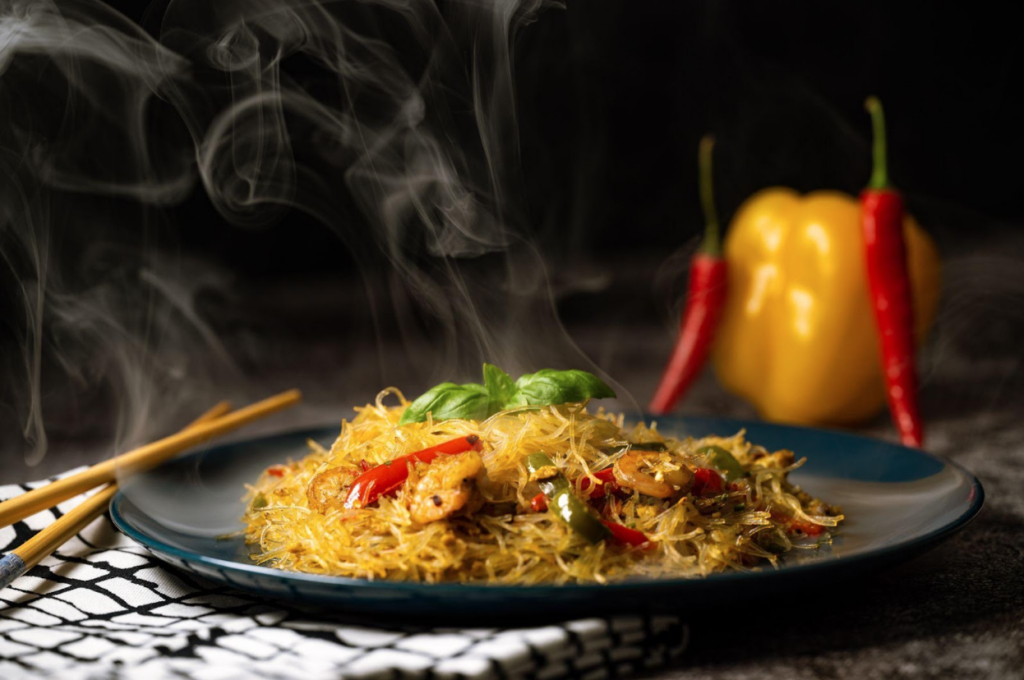 Smoky Asian salad with glass noodles, chicken, prawn, shrimp, and vegetables on a gray background.